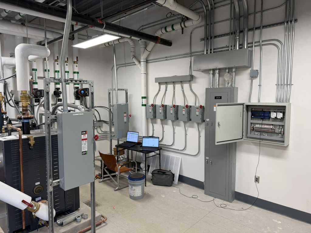 Mechanical room with a controls panel and commissioning laptops